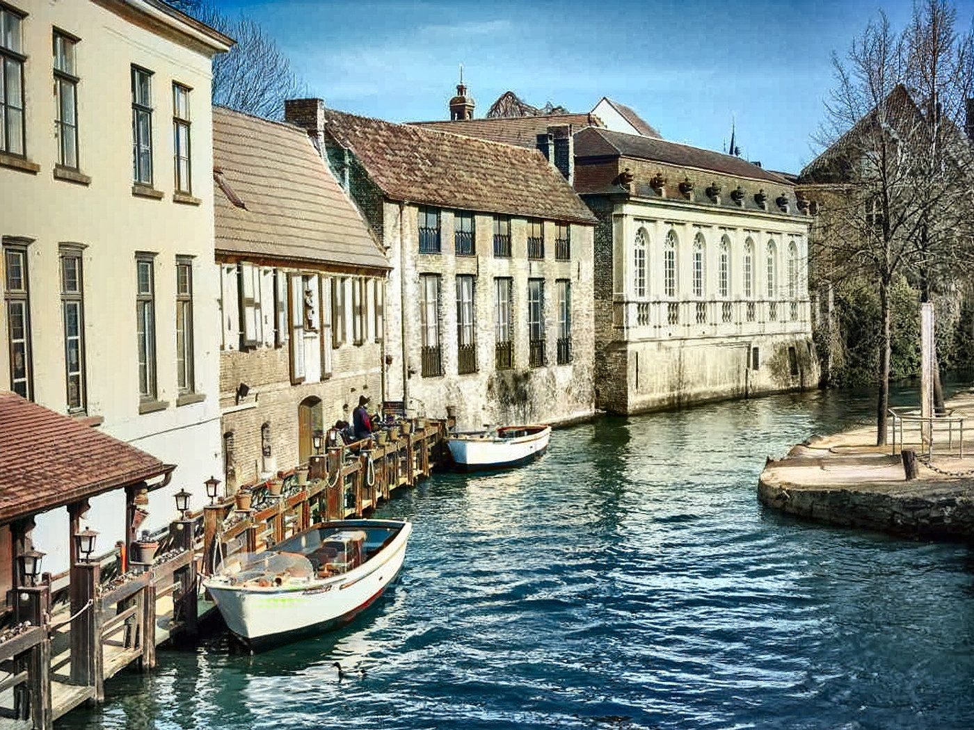 A Bruges canal restored in colour: brick gables, water and sky